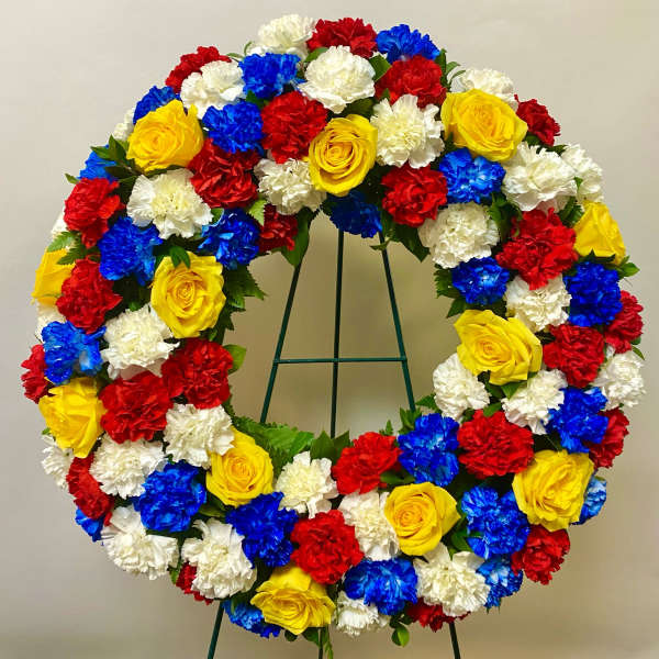 Circular wreath of red, white, blue, and yellow flowers on a stand