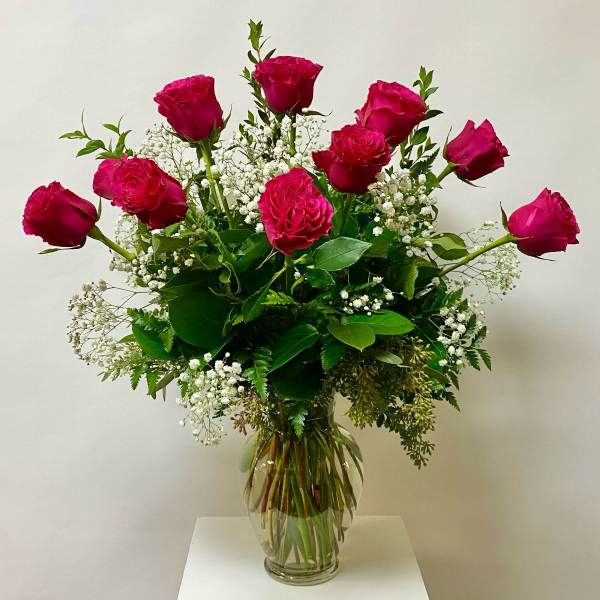 Pink roses arranged in a clear glass vase with white baby's breath