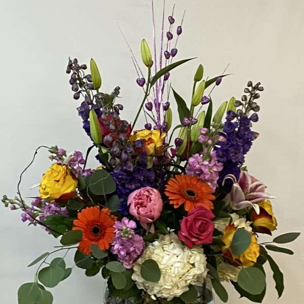 Colorful mixed bouquet in a glass vase with tall purple accents