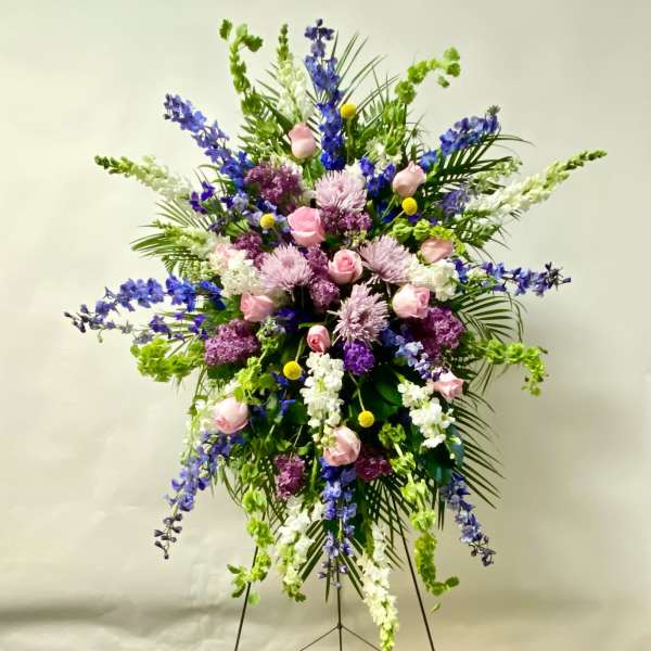Large standing floral spray with pink roses, purple blooms, and white flowers