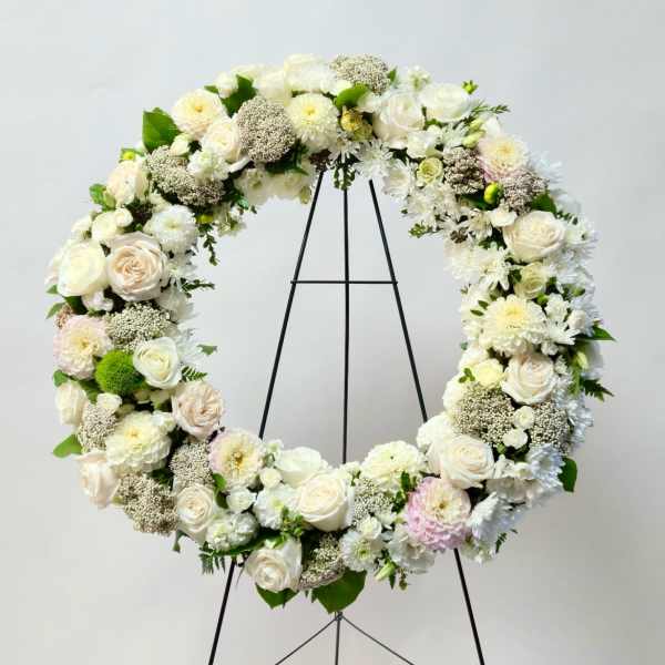 Large white floral wreath on a black stand