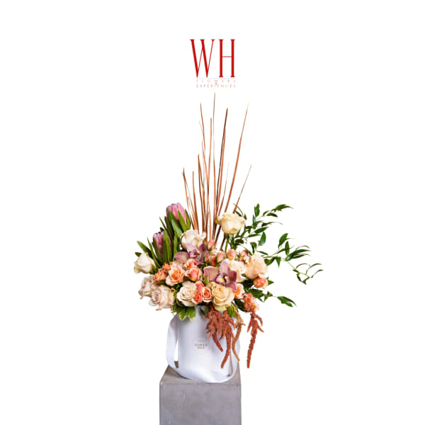 Tall floral arrangement in a white bag-style container with pink and cream blooms