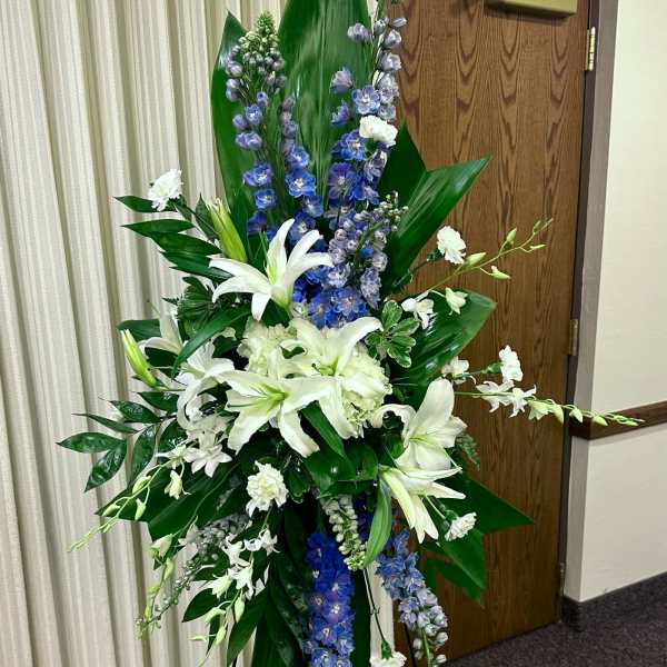 Tall white and blue floral standing spray on an easel