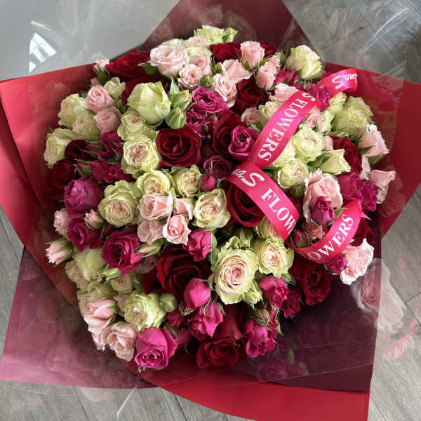 Large bouquet of red, pink, and cream roses wrapped in red paper