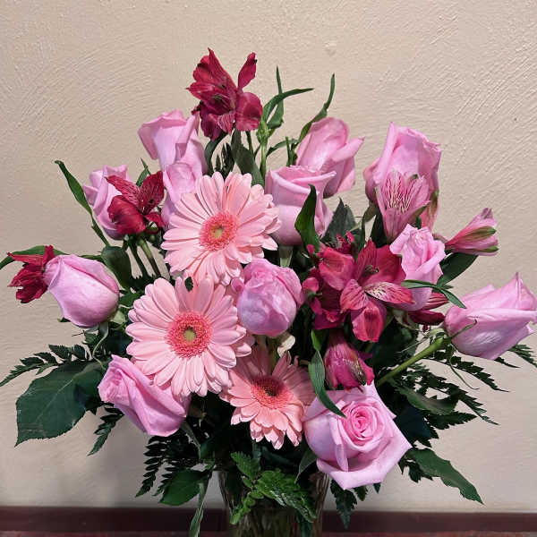 Pink roses, gerbera daisies, and alstroemeria in a glass vase