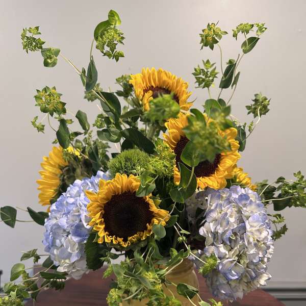 Sunflowers and blue hydrangeas in a yellow vase