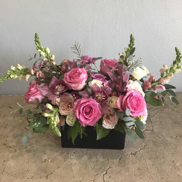 Pink roses and purple orchids in a black rectangular container