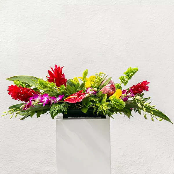 Bright mixed tropical flower arrangement in a rectangular container