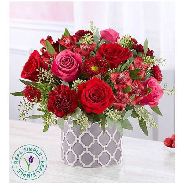Red and pink rose bouquet in a patterned gray vase