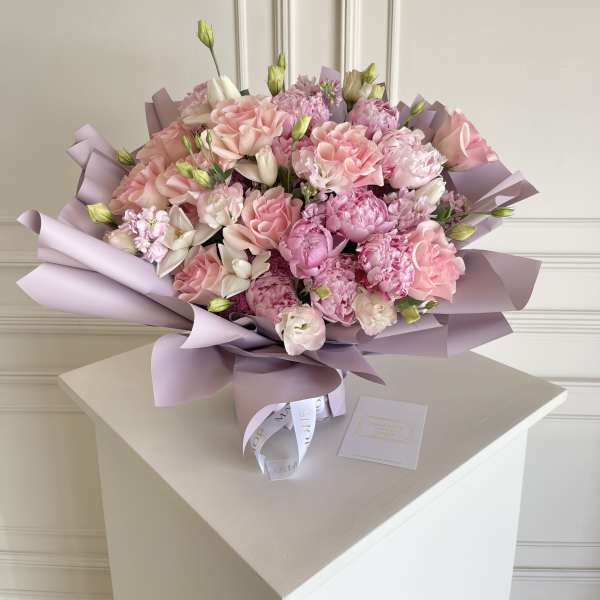 Pink bouquet with roses and carnations wrapped in lavender paper