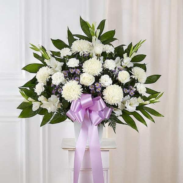 White floral arrangement with a lavender ribbon in a clear vase