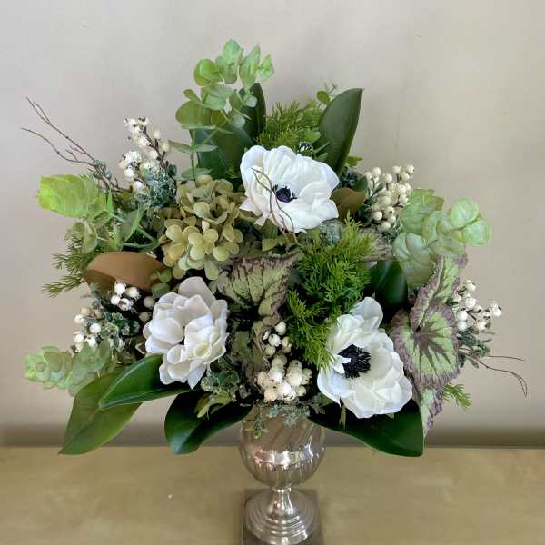 White flowers arranged in a silver vase with mixed greenery
