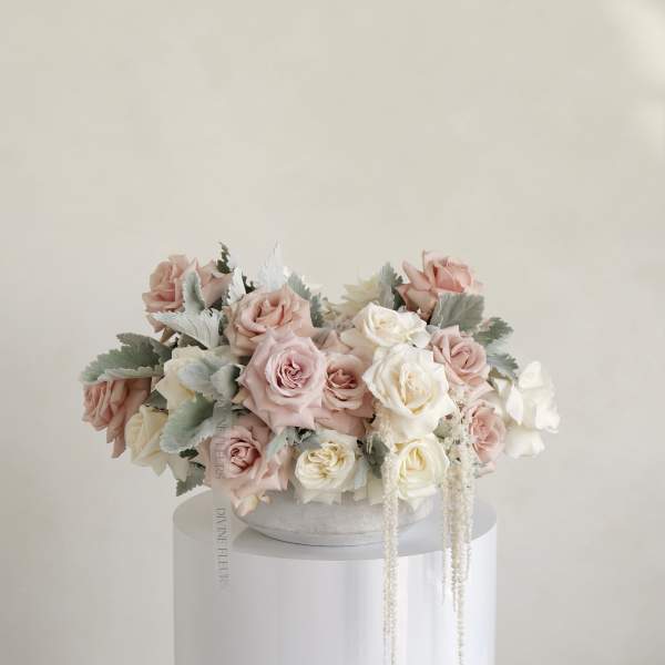 Blush and white roses arranged in a low round box.