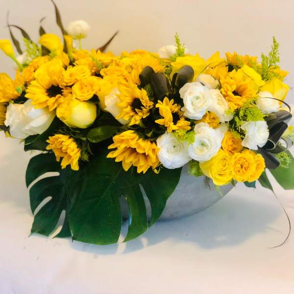 Yellow and white floral arrangement in a low gray bowl