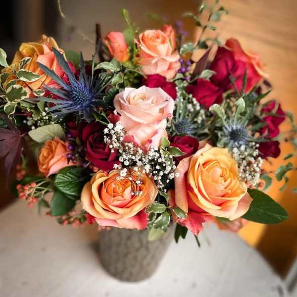 Bouquet of peach and red roses in a gray vase