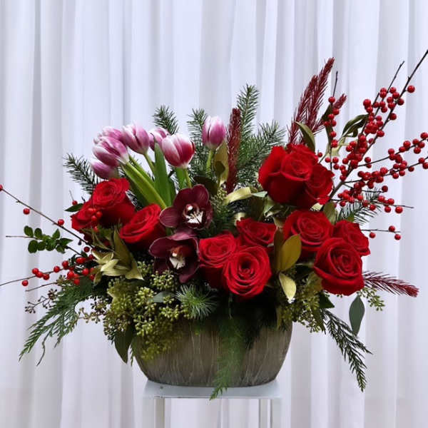 Red roses and pink tulips in a low vase with berry branches