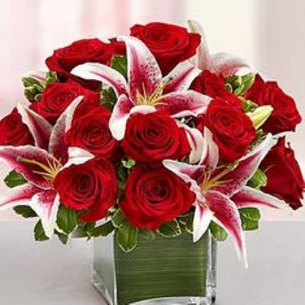Red roses and pink lilies arranged in a square glass vase