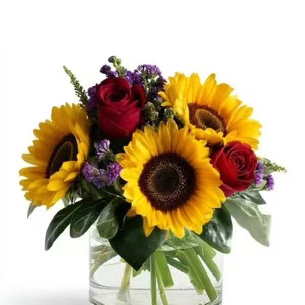 Sunflowers and red roses arranged in a clear glass vase
