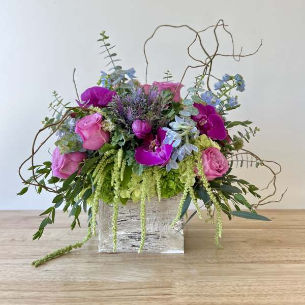 Pink and purple floral arrangement in a rustic wooden box