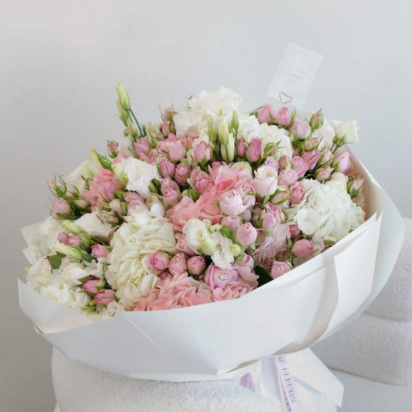 Large bouquet of pink and white roses wrapped in white paper
