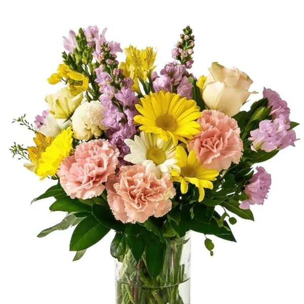 Mixed bouquet of yellow, pink, and white flowers in a clear glass vase
