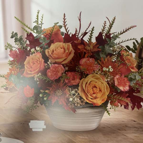 Orange roses and autumn flowers in a white bowl vase