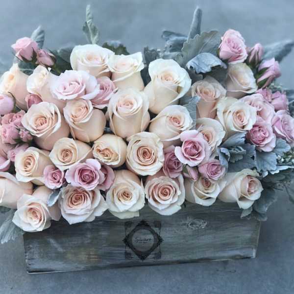 Arrangement of pale pink and cream roses in a wooden box