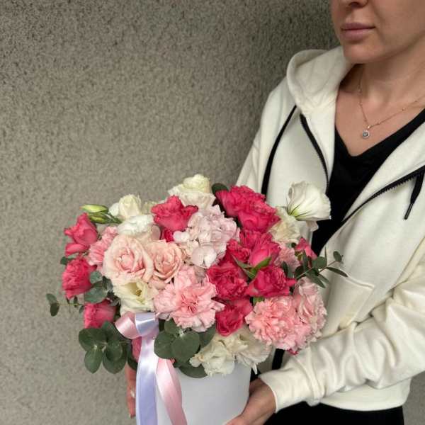 Woman holding a white hatbox of pink and white flowers with ribbon