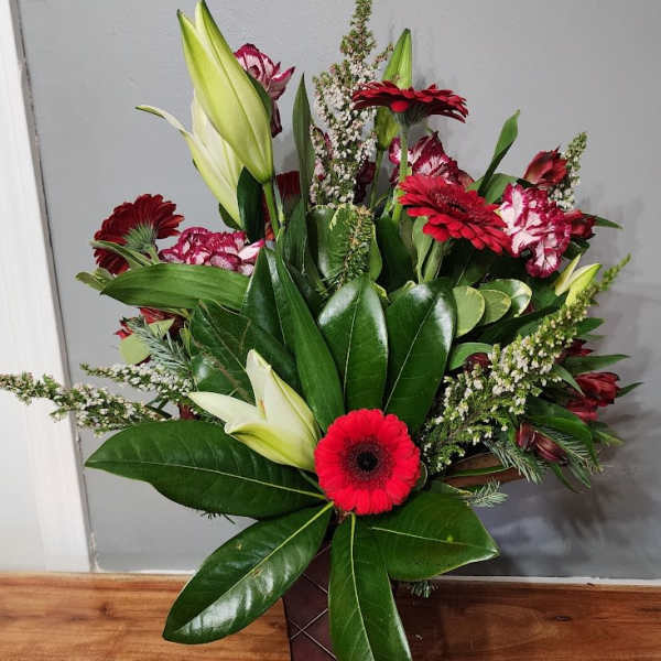 Mixed bouquet with red gerbera daisies, lilies, and carnations in a vase