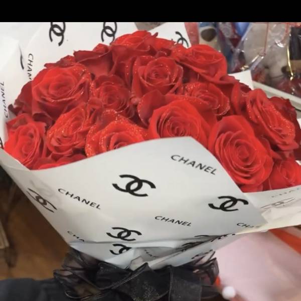 Bouquet of red roses wrapped in white Chanel paper with a black ribbon