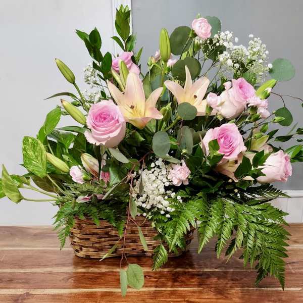 Pink roses and lilies arranged in a wicker basket