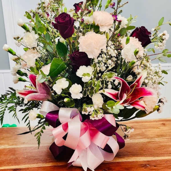 Bouquet of dark roses, white carnations, and pink lilies with ribbon