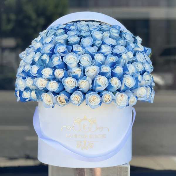 Blue and white roses arranged in a round white hat box