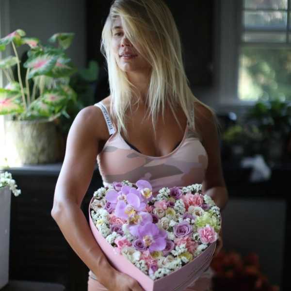 Woman holding a heart-shaped box of pastel flowers