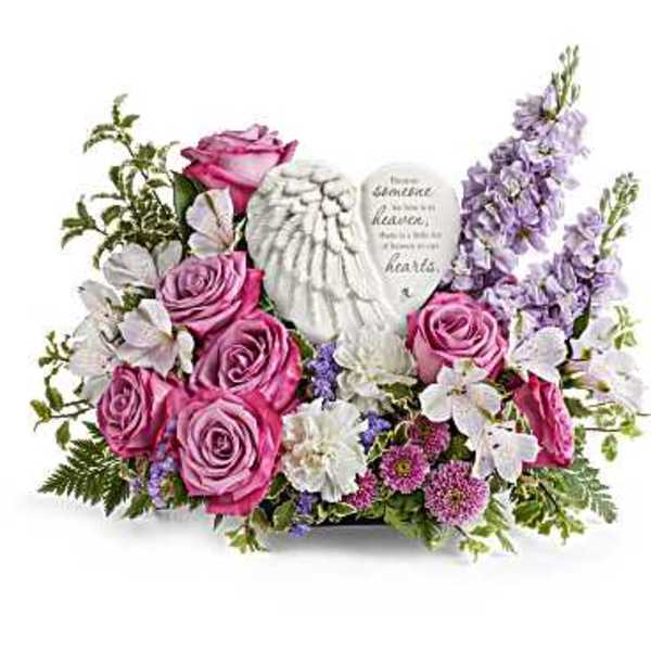 Pink roses and white flowers arranged around a memorial heart plaque