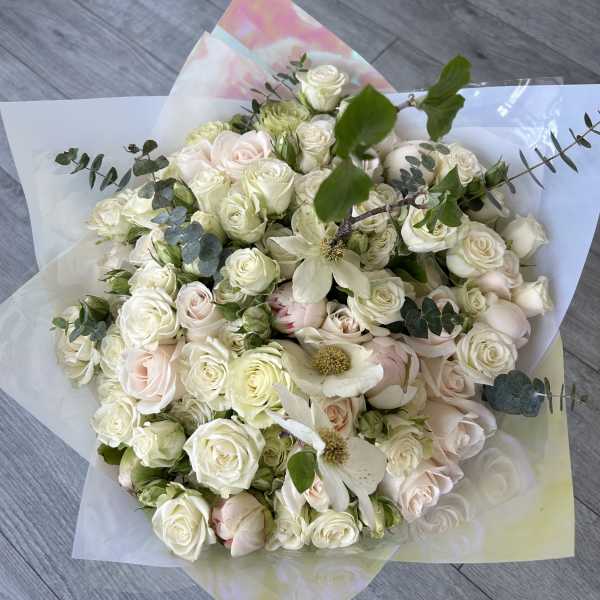 Bouquet of white and blush roses with greenery in pastel wrapping
