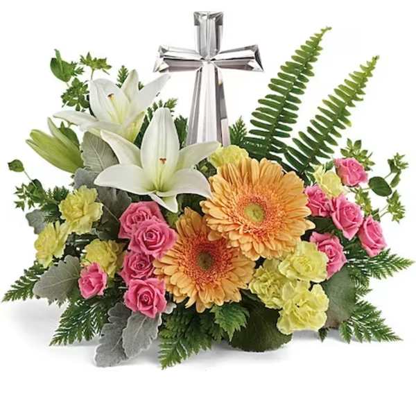 Floral arrangement with white lilies, pink roses, and orange gerbera daisies topped by a silver cross