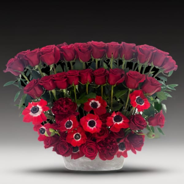 Red roses and anemones arranged in a clear vase