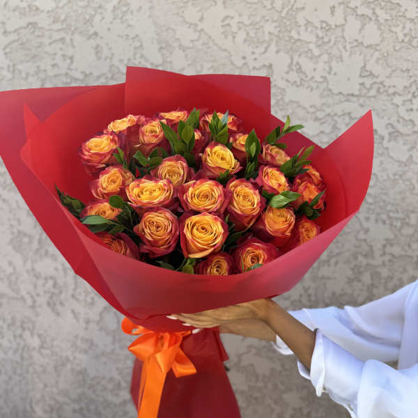Bouquet of yellow-orange roses wrapped in red paper with an orange ribbon