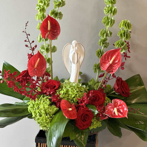 Red roses and anthuriums with green hydrangeas and a small angel figurine