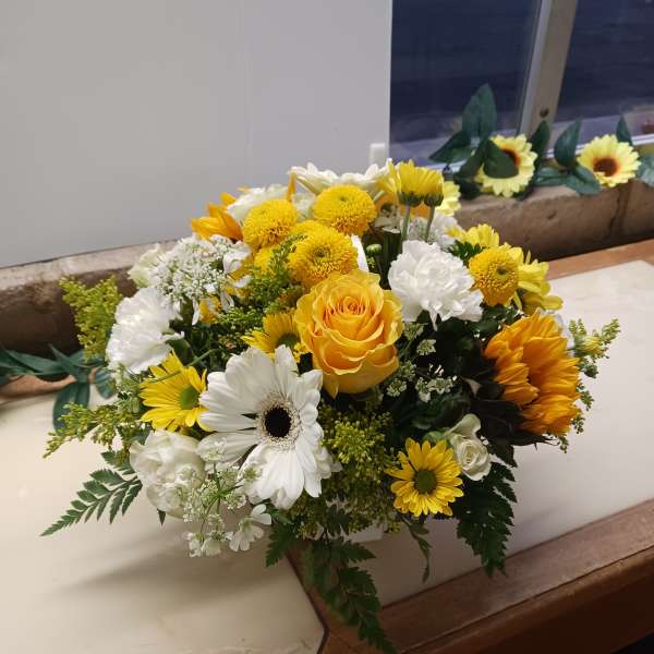 Yellow and white mixed flower arrangement in a white container