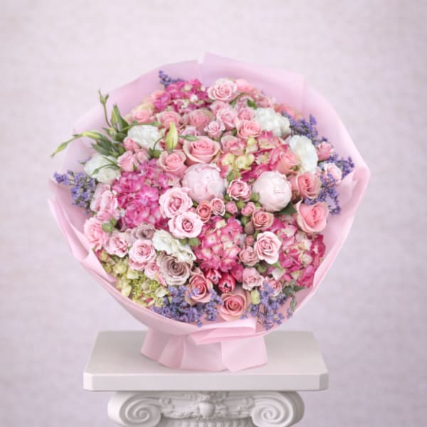 Large bouquet of pink roses and mixed blooms wrapped in pink paper