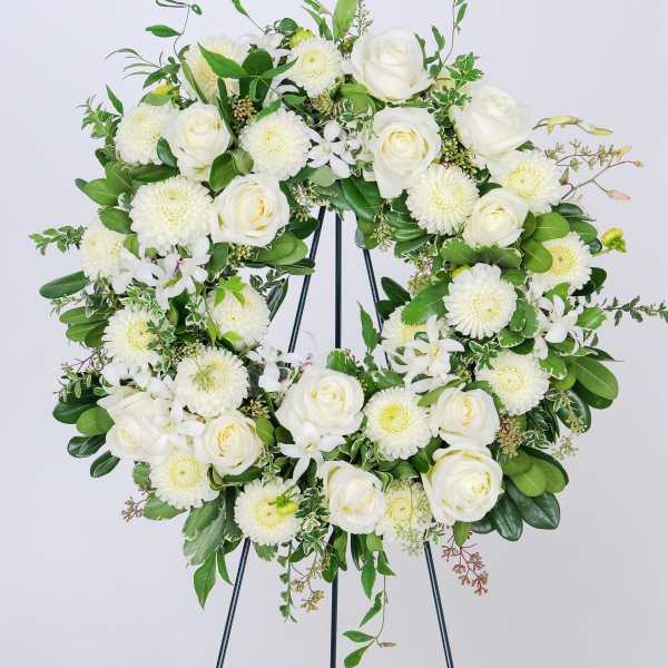 White rose and chrysanthemum wreath on a black stand