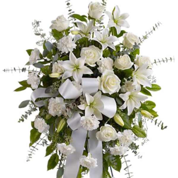 White floral standing spray with lilies, roses, and ribbon