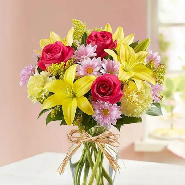 Bouquet of pink roses and yellow lilies in a clear glass vase