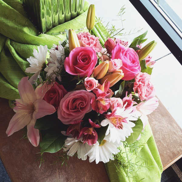 Pink bouquet with roses, lilies, and daisies wrapped in green paper
