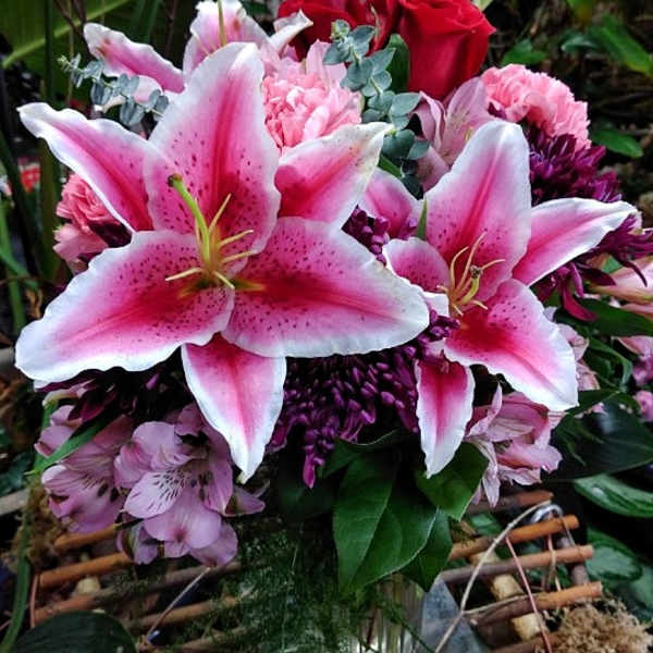 Bouquet of pink lilies and red roses in a glass vase