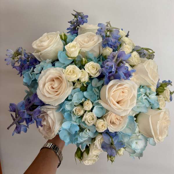 Bouquet of white roses, blue hydrangeas, and purple flowers