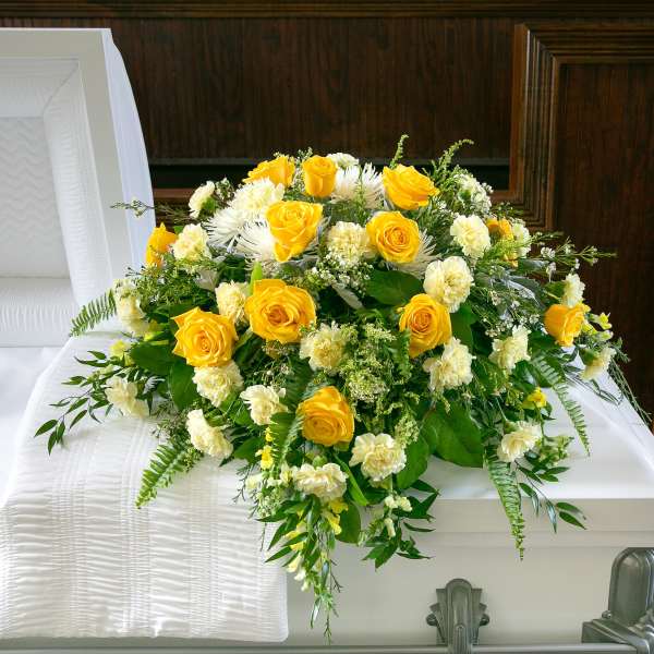 Yellow and white floral spray on a white casket