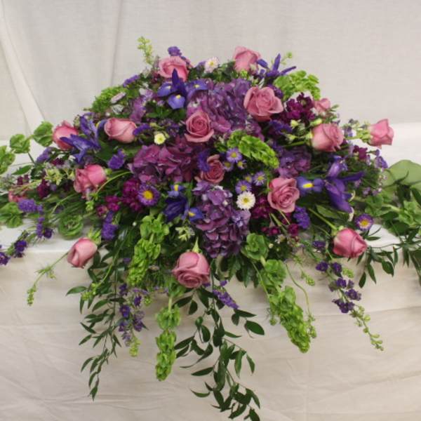 Large purple and pink floral arrangement with trailing greenery